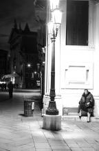 signora seduta in un angolo sotto un lampione